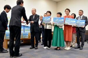 政府側(手前)に署名を渡す議連メンバーら=18日午後、国会内
