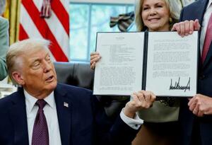 ホワイトハウスで署名した覚書を誇示するトランプ米大統領=15日、ワシントン(ロイター=共同)