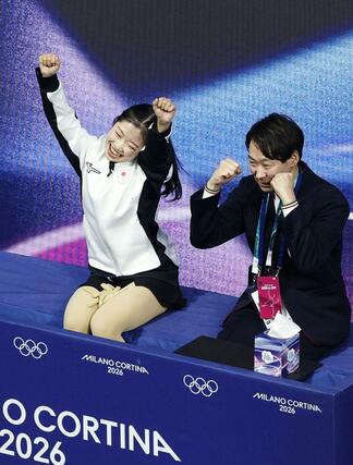 女子ＳＰの得点を確認し、喜ぶ中井亜美。右は中庭健介コーチ＝ミラノ（共同）