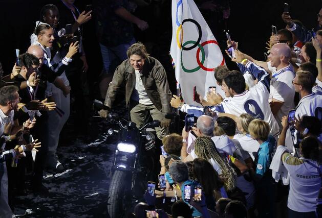 パリ五輪の閉会式で、五輪旗をバイクで運ぶトム・クルーズさん＝８月１１日、パリ郊外（共同）