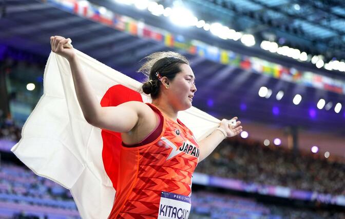 女子やり投げで金メダルを獲得し、日の丸を掲げる北口榛花＝パリ郊外（共同）
