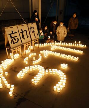 キャンドルに手を合わせ、祈りをささげる市民ら=3月12日午後6時30分ごろ、十日町市本町2