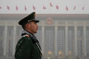 　全人代が行われる北京の人民大会堂（奥）周辺で警戒する治安当局者＝４日（共同）