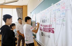 胎内ディアーズの小川悠樹さん(右から2人目)が見守る中、横断幕にメッセージを書き込む築地小児童=胎内市築地