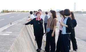 柏崎市の職員を前に、東日本大震災の津波被害や東京電力福島第1原発事故について語る「富岡町3・11を語る会」の青木淑子代表(中央)。後ろに見えるのは福島第2原発=福島県双葉郡富岡町