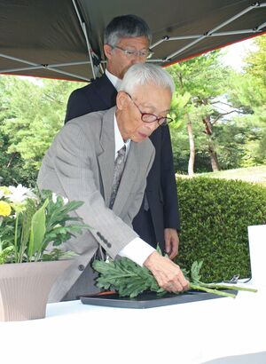 満州柏崎村の塔の前で慰霊の献花を行う巻口弘さん(手前)=柏崎市緑町