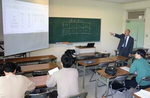 学生に経済効果の分析の仕方について説明する黒岩直専任講師(奥)=柏崎市軽井川の新潟産業大