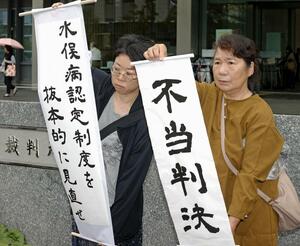 水俣病患者認定を巡る訴訟の判決で、「不当判決」などと書かれた紙を掲げる支援者ら＝２３日午後、福岡高裁前