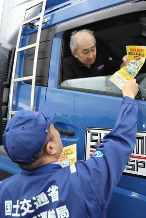 トラック運転手にチラシを配り、長時間の荷待ちなどがないか情報提供を呼びかけるトラック・物流Gメン=11月、新潟市西区