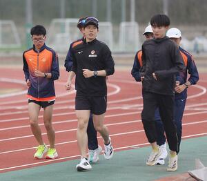 練習終盤のジョギングで選手に語りかけながら走る鈴木雄介コーチ(中央)=新潟市北区