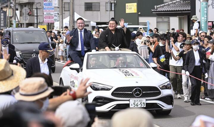 石川県津幡町で行われた大相撲の横綱昇進を祝うパレードで、沿道に集まった人たちの声援に応える大の里関。左は二所ノ関親方＝２９日午後