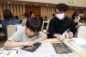スクラッチアートで打ち上げ花火を描く親子=長岡市千秋3