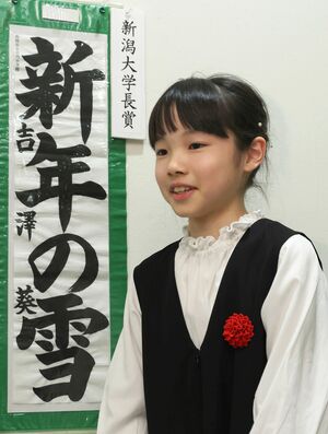 新潟大学書道教育学会が主催する書道の全国大会3部門で最高賞に輝き喜ぶ吉澤葵さん。左は書初の受賞作品=2月18日、新潟市中央区