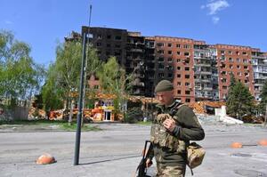 ロシアとの戦闘で損傷した建物の前を歩くウクライナ兵=4月23日、ウクライナ東部ドネツク州のポクロウシク(AP=共同)