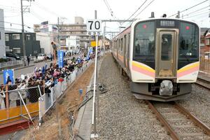 開業した上所駅を発着する列車。地元住民らが手やうちわを振って出迎えた=3月15日、新潟市中央区