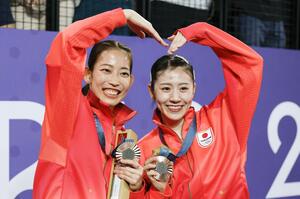バドミントン女子ダブルスで銅メダルを獲得し、笑顔でポーズをとる志田千陽(右)と松山奈未=パリ(共同)