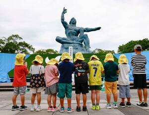 平和公園を訪れ、平和祈念像の前で手を合わせる園児たち=8日午後、長崎市