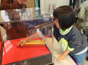 「金塊」をつかんで箱から出そうと奮闘する参加者=31日、新潟市西区の新潟ふるさと村