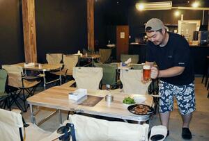 店内がアウトドア風インテリアのTAMARIVAで料理やビールを提供する店主の山井貴志さん=三条市本町2