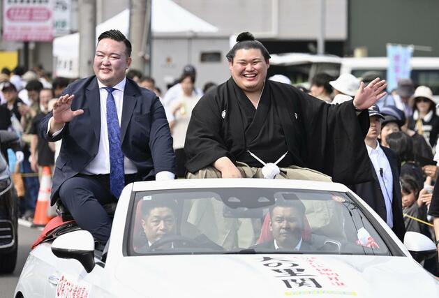 石川県津幡町で行われた大相撲の横綱昇進を祝うパレードで、沿道に集まった人たちの声援に応える大の里関。左は二所ノ関親方＝２９日午後