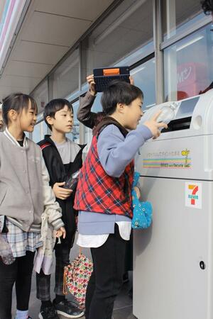 ペットボトルを回収機に投入する有明台小の児童=新潟市中央区有明大橋町