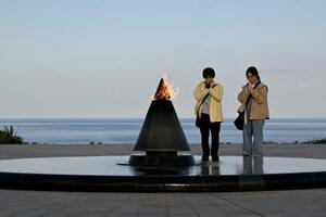 平和祈念公園で手を合わせる親子。母親は「戦争を知らない世代なので子どもにも伝えなくては」と語った＝３月、沖縄県糸満市