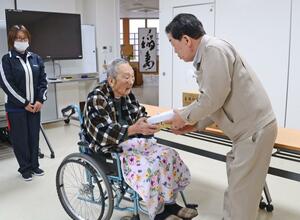 玉垣哲郎社長(右)から「妻有そば」を受け取る入居者の男性=12月25日、十日町市川治