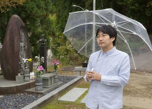 自宅のあった場所に立つ慰霊碑前で、亡き妹の思い出を語る星野匡裕さん=小千谷市塩谷