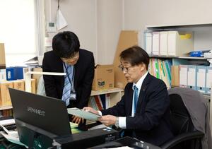 今月から粟島浦村の総務課長を務める小林英三さん(右)=4月14日、粟島浦村役場