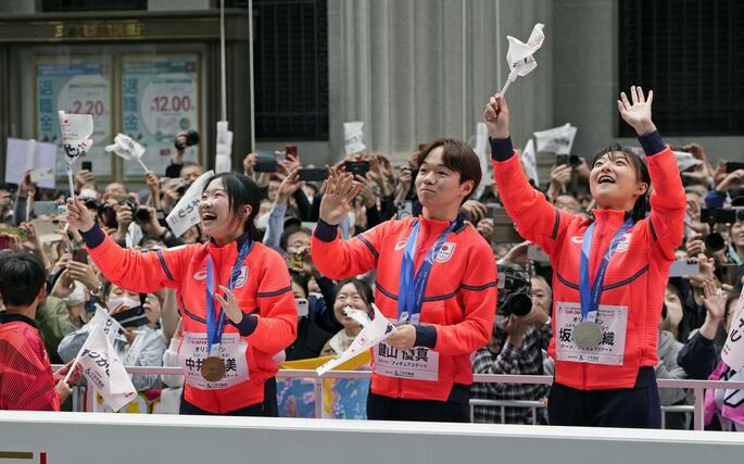 東京・日本橋でパレードし、歓声に応えるフィギュアスケートの（左から）中井亜美、鍵山優真、坂本花織＝２５日午前