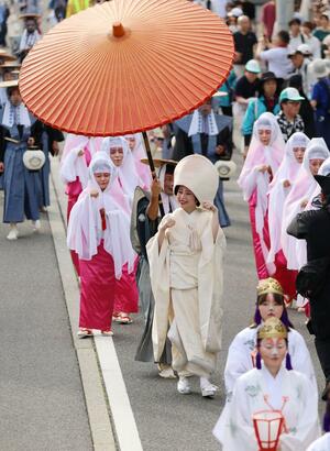 観客の祝福を受けながら歩く花嫁ら=6日、阿賀町津川