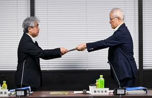 厚労省で開かれた中央最低賃金審議会で、岸本武史労働基準局長(左)に答申書を手渡す藤村博之会長=4日午後