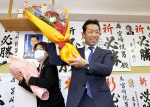 小千谷市長選で初当選し、花束を受け取る宮崎悦男さん=11月13日、小千谷市若葉3の選挙事務所