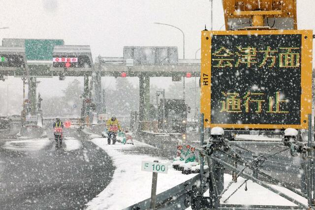 大雪の影響で通行止めとなった磐越道の安田IC。福島県方面への通行止めの表示が出て、係員が誘導に当たった=2月5日、阿賀野市