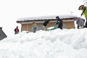 民家の２階の高さで除雪する連合東京青年委員会のメンバー＝柏崎市高柳町高尾
