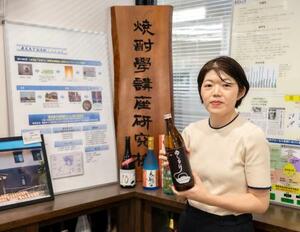 　鹿児島大の研究センター内で焼酎を持つ吉崎由美子准教授＝鹿児島市