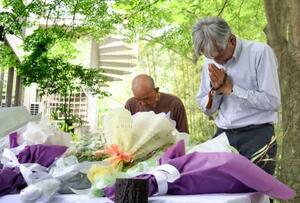 空自機墜落事故から1年となり、献花台の前で手を合わせる人たち=14日午後、愛知県犬山市