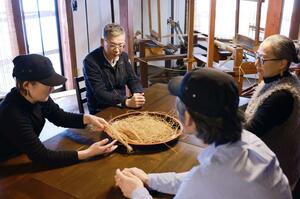 
カフェスペースで打ち合わせをする社長の二野一寿さん（左から２人目）と社員たち＝村上市山熊田
