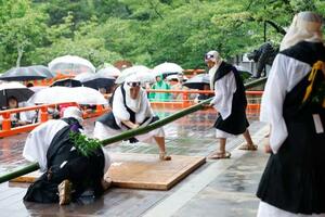鞍馬寺の「竹伐り会式」で、大蛇に見立てた青竹をたたき切る僧兵姿の男性=20日午後、京都市左京区