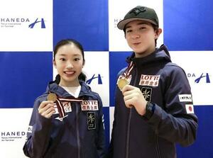 　フィギュアスケートのジュニアＧＰシリーズ第１戦ラトビア大会から帰国し、金メダルを手に撮影に応じる中田璃士（右）と岡田芽依＝２５日、羽田空港