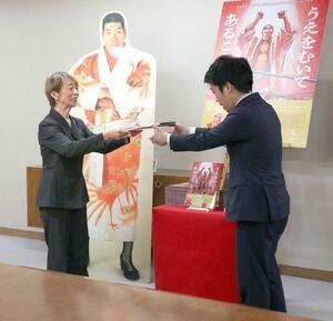 ジャイアント馬場さんの伝記絵本を寄贈するめいの緒方理咲子さん(左)=三条市役所