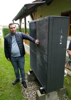 導入したパナソニックのヒートポンプ式暖房機の室外機と利用者のクリストフ・ラウフマンさん=28日、ドイツ南部バイエルン州(共同)