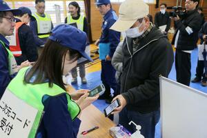 県原子力防災訓練でスマートフォンを使った受け付けを試す住民たち＝１１月、新潟市西蒲区