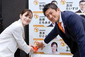 東京選挙区で当選を決めたさや氏(左)と花を付ける参政党の神谷代表=20日午後9時11分、東京都新宿区