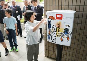 ラッピングポストにはがきを投かんする津川小児童ら＝阿賀町役場