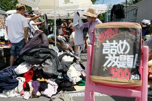 フリーマーケットの詰め放題コーナーで買い物する人たち=6日、東京都品川区