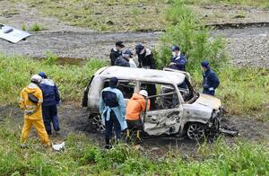 乗用車から焼死体が見つかり、状況を調べる警察関係者ら＝５月２９日午前１１時半過ぎ、南魚沼市欠之上