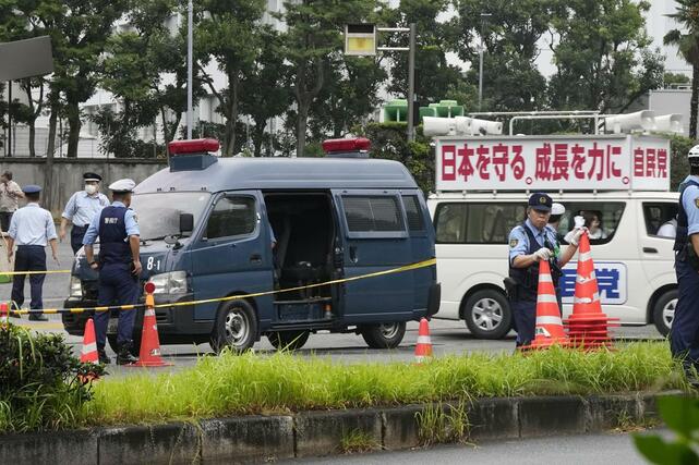 火炎瓶のようなものが投げ込まれた自民党本部付近。警察車両の前部が変色していた。後方は党本部から出る街宣車＝１０月１９日午前７時４８分、東京・永田町