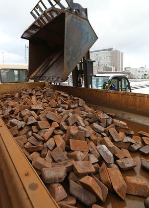 コンテナから大型ダンプに積み替えられる鉄材。ごう音と共に鉄粉が舞う＝長岡市千歳１