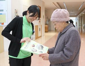 新潟大のボランティアサークル「ささだんご」の活動史を浪江町の住民に手渡す卒業生＝１５日、福島県浪江町